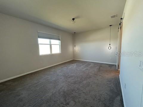 An empty bedroom features gray carpeting, light-colored walls, a window, and two hanging pendant lights — 228 HILLCREST DRIVE, DUNDEE, FL