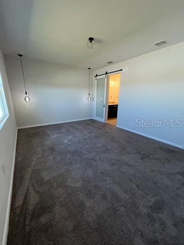 A bedroom with gray carpet, two pendant lights, and a sliding barn door to a bathroom — 228 HILLCREST DRIVE, DUNDEE, FL