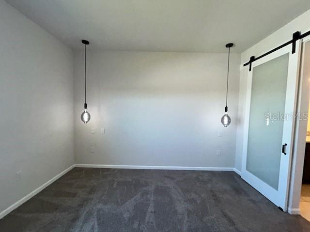 A room with gray carpet, two hanging pendant lights, and a white sliding barn door — 228 HILLCREST DRIVE, DUNDEE, FL