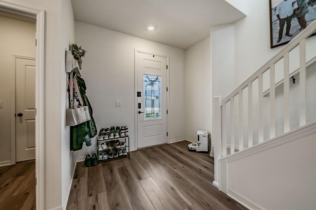 An entryway features wood-look flooring, a white front door, a staircase, and a shoe rack — 37668 YUKON DRIVE, ZEPHYRHILLS, FL