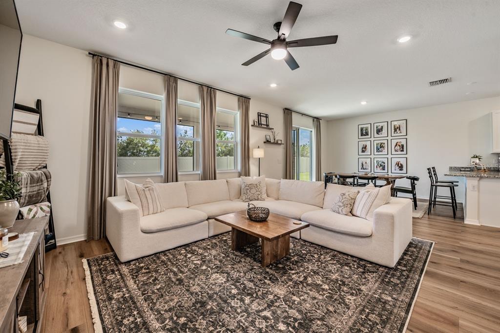 A living room features a large white sectional, wood coffee table, and dark area rug — 37668 YUKON DRIVE, ZEPHYRHILLS, FL