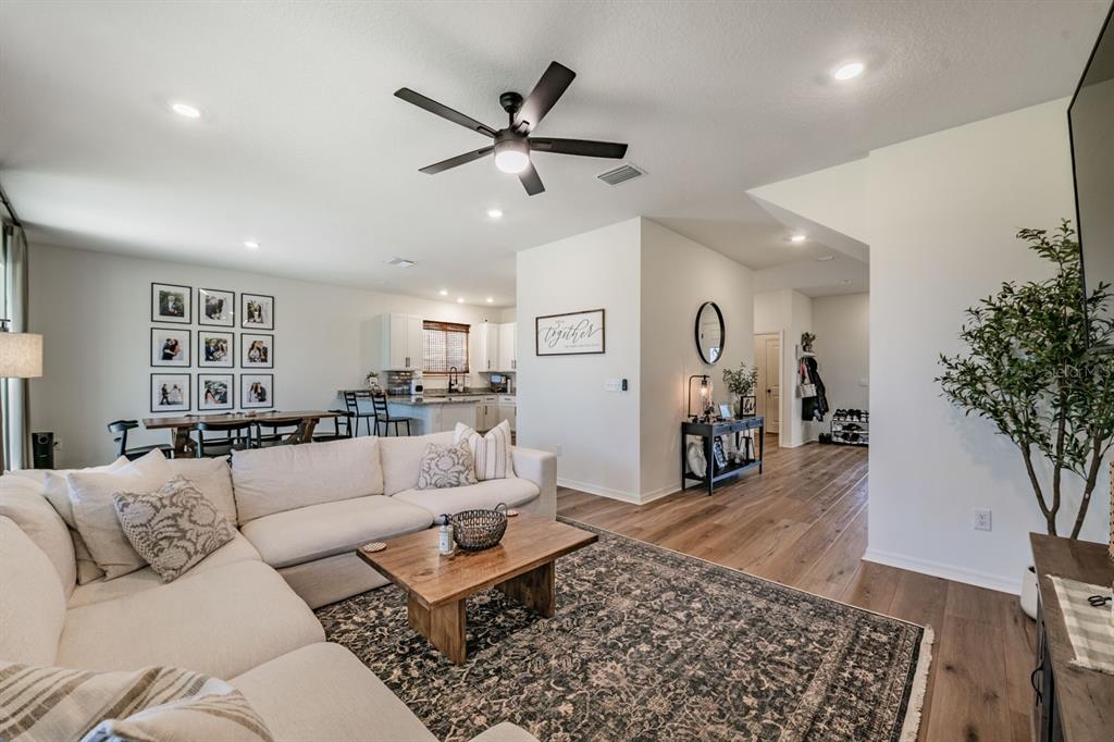 A living room with a white sectional sofa, wood coffee table, and open kitchen area — 37668 YUKON DRIVE, ZEPHYRHILLS, FL