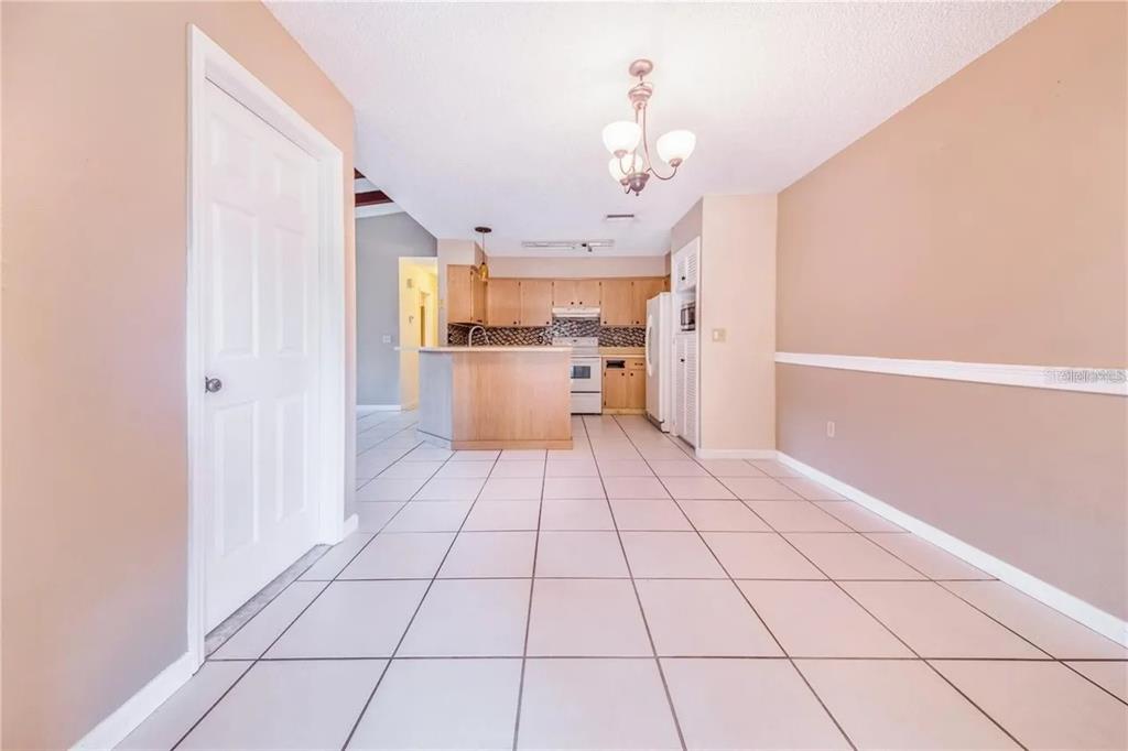 A dining area with tile floors leads to an open kitchen with light wood cabinets — 733 MIKASUKI DRIVE, LAKELAND, FL