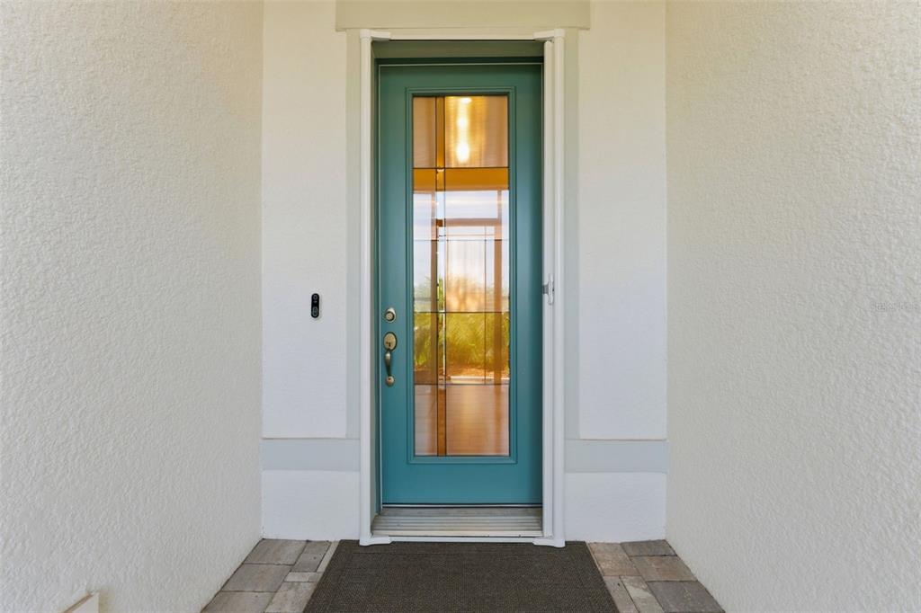A teal front door with a glass insert is centered in a white stucco entryway — 11353 OUTRIGGER PLACE, PARRISH, FL