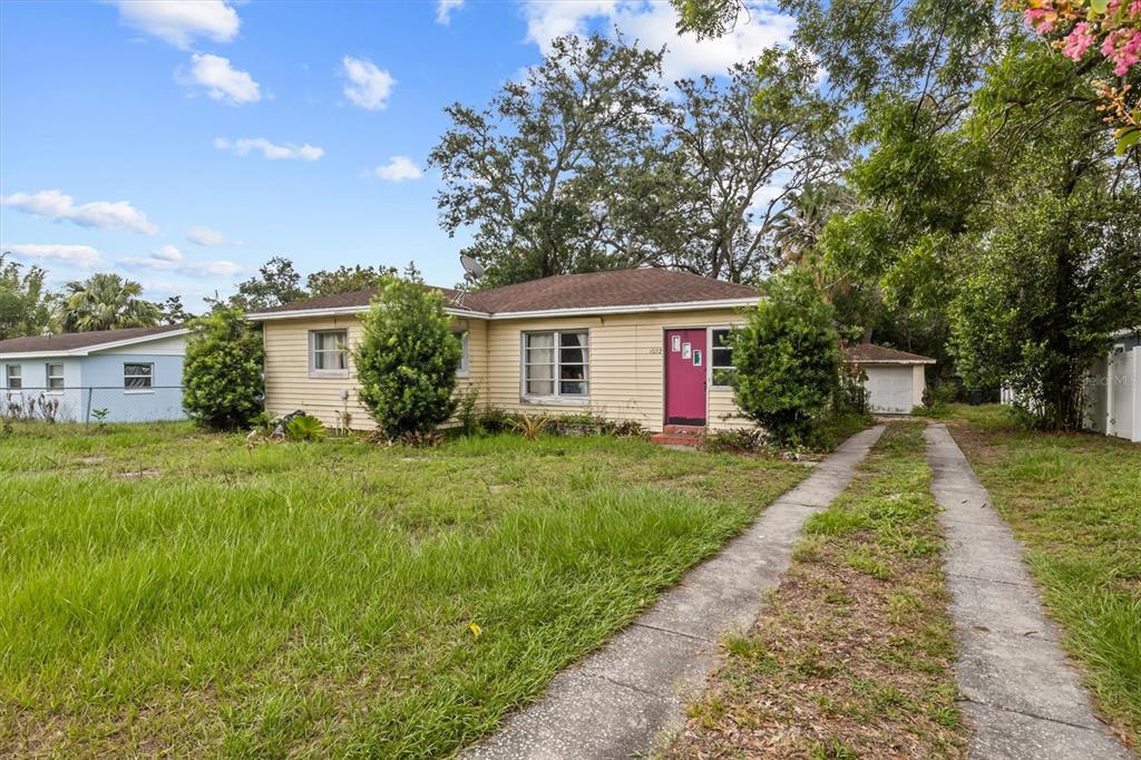 A single-story house with yellow siding, a bright pink front door, and a concrete driveway — 1022 W MARJORIE STREET, LAKELAND, FL