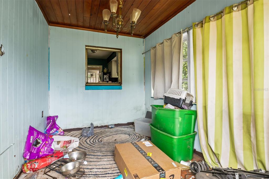 A sunroom with light blue wood-paneled walls, a wood-plank ceiling, and a pass-through window — 1022 W MARJORIE STREET, LAKELAND, FL