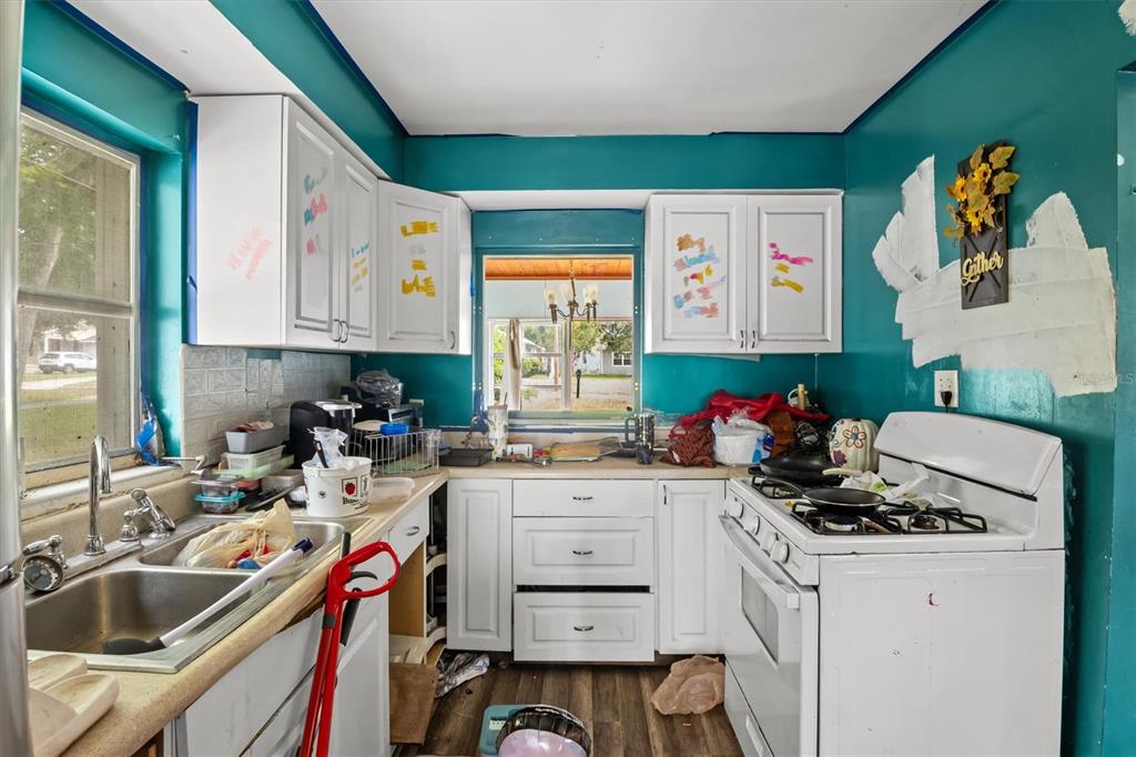A kitchen with teal walls, white cabinets, a double sink, and a white gas stove — 1022 W MARJORIE STREET, LAKELAND, FL