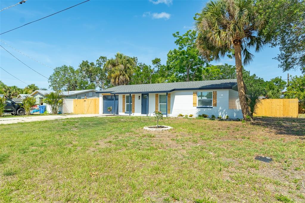 A single-story white house with a dark roof, blue trim, and a large front yard — 6304 FLORIDA CIRCLE W, APOLLO BEACH, FL