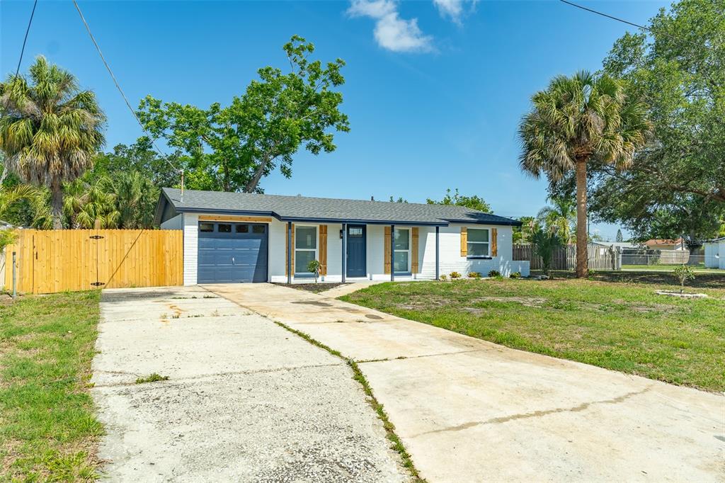 A single-story white house with a blue garage door and a wooden fence — 6304 FLORIDA CIRCLE W, APOLLO BEACH, FL