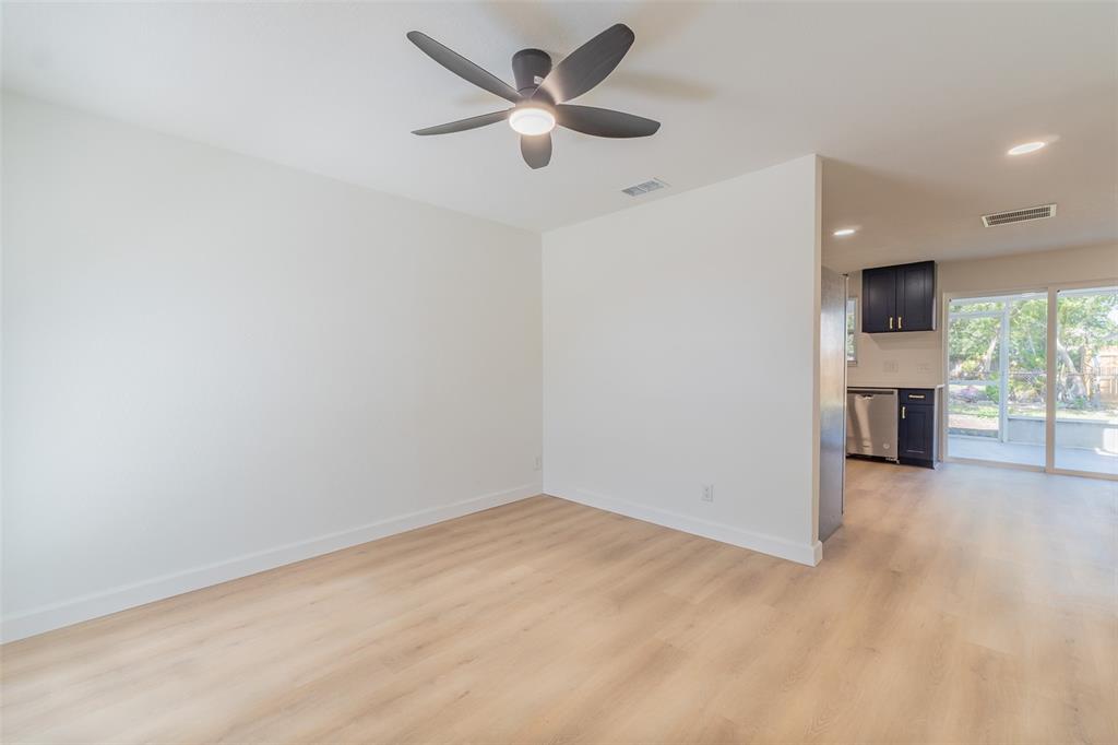 An empty room with light wood-look flooring, a ceiling fan, and an adjacent kitchen area — 6304 FLORIDA CIRCLE W, APOLLO BEACH, FL