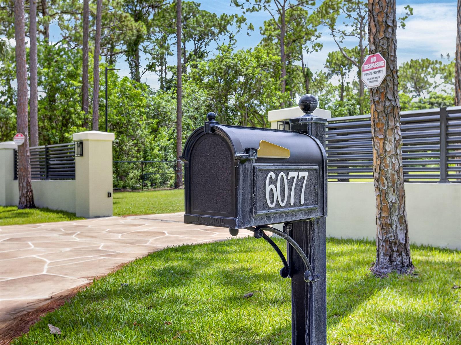A black mailbox with the number 6077 stands on a post in front of a fence — 6077 NW 71st Terrace, Parkland FL 33067, PARKLAND, FL