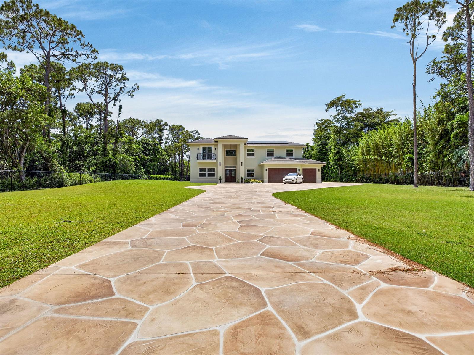 A two-story house with a stone-patterned driveway sits on a large, grassy lot — 6077 NW 71st Terrace, Parkland FL 33067, PARKLAND, FL
