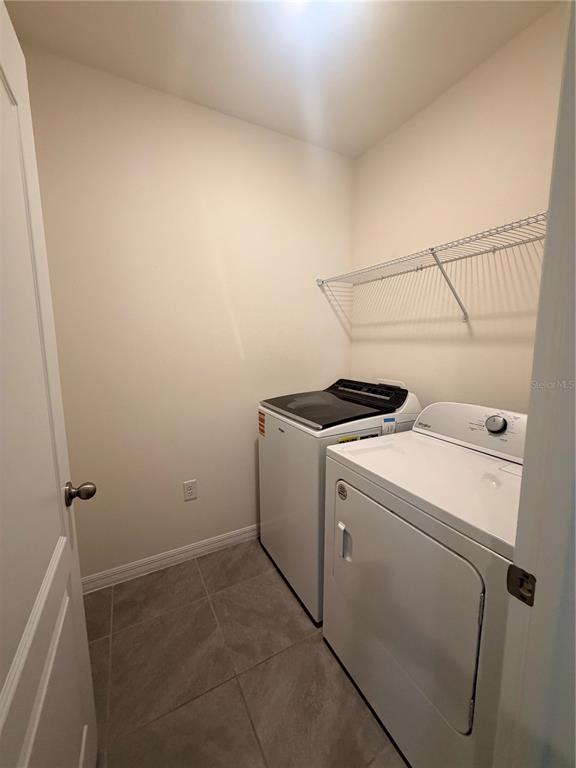 A laundry room with tile flooring, a white washer and dryer, and a wire shelf — 33426 AFFIRMED WAY, SORRENTO, FL