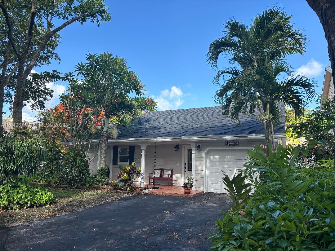 A single-story house with white siding, a shingled roof, a garage, and lush landscaping — 15110 SW 141st Ct, Miami FL 33186, MIAMI, FL