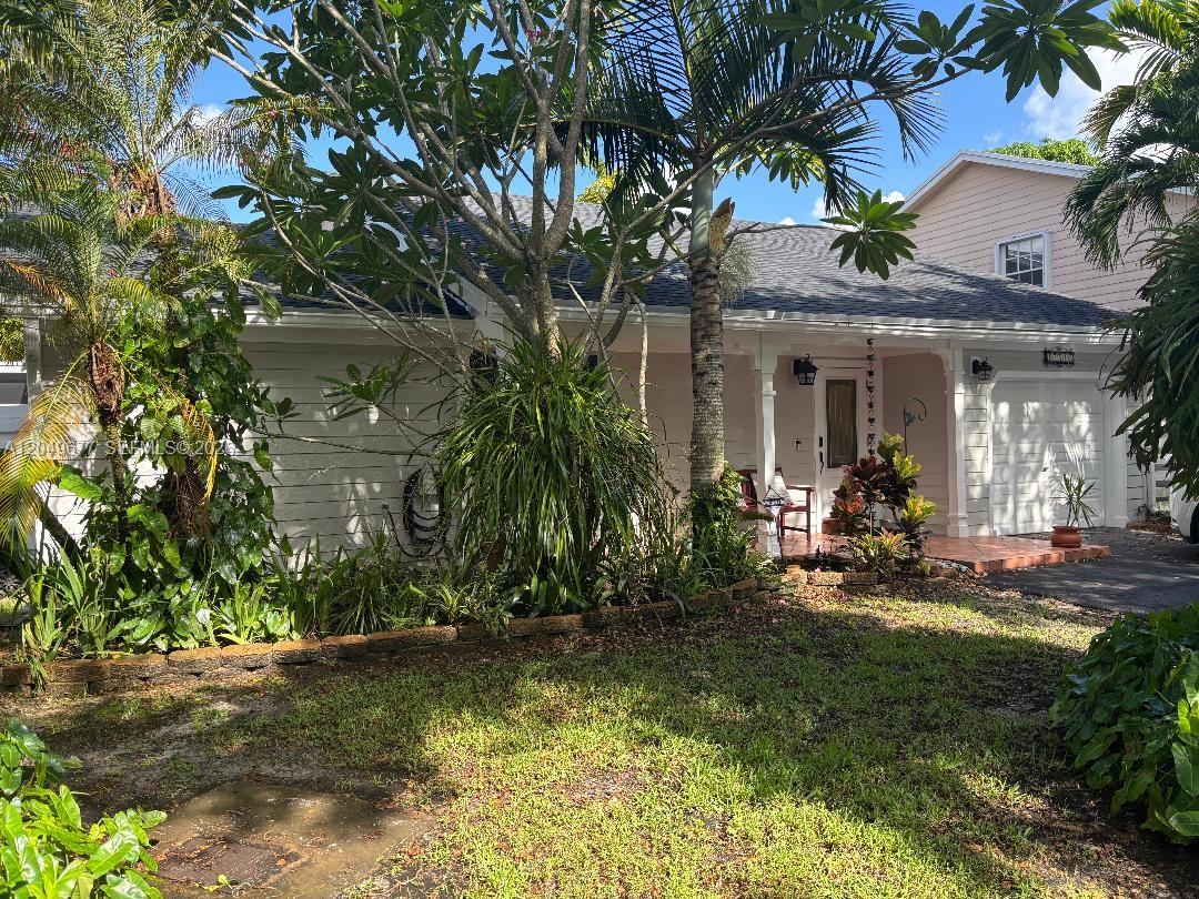 A white single-story house features a covered porch, a garage, and lush landscaping — 15110 SW 141st Ct, Miami FL 33186, MIAMI, FL