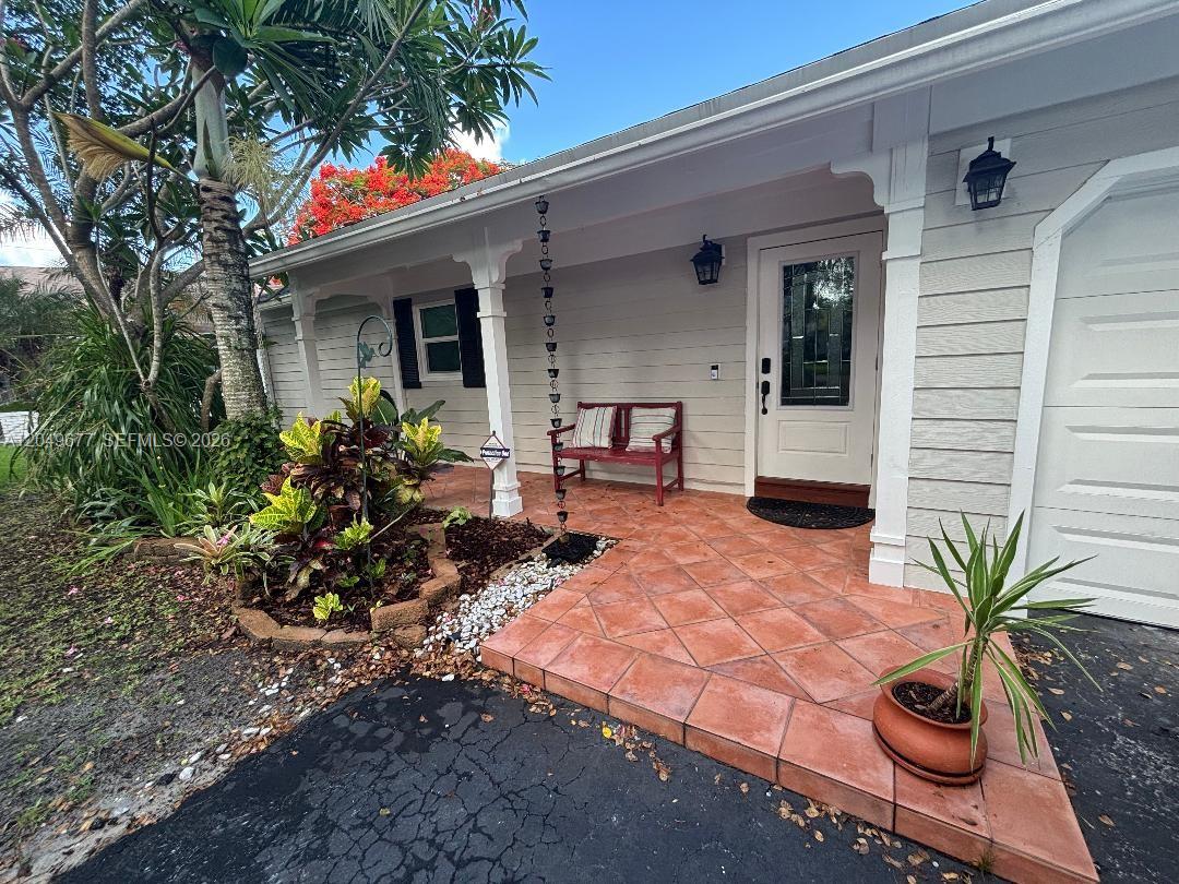 A front porch with terracotta tiles, a red bench, and a rain chain — 15110 SW 141st Ct, Miami FL 33186, MIAMI, FL
