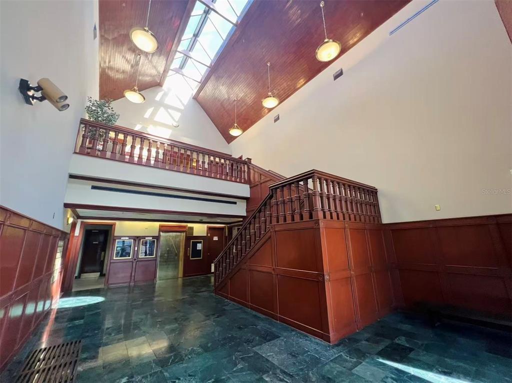A high-ceilinged lobby features a wooden staircase, a balcony, and a large skylight — 2500 W LAKE MARY BOULEVARD UNIT 213, LAKE MARY, FL