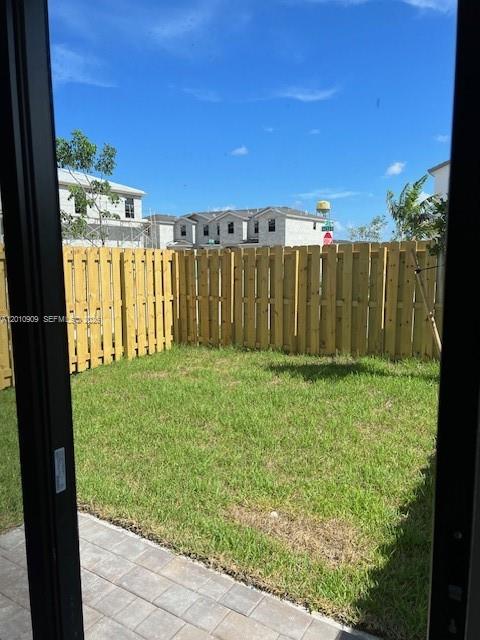 A view of a small grassy backyard enclosed by a wooden fence — 13102 SW 232nd Ln # 13102, Miami FL 33032, MIAMI, FL