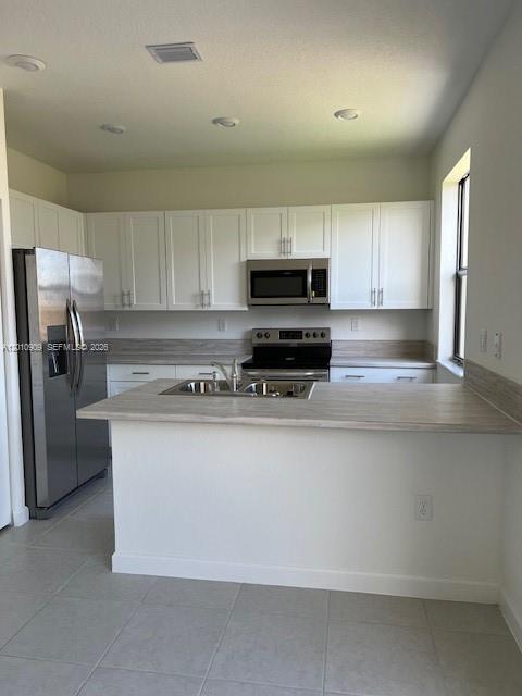 A kitchen features white cabinets, stainless steel appliances, and a light-colored countertop island — 13102 SW 232nd Ln # 13102, Miami FL 33032, MIAMI, FL