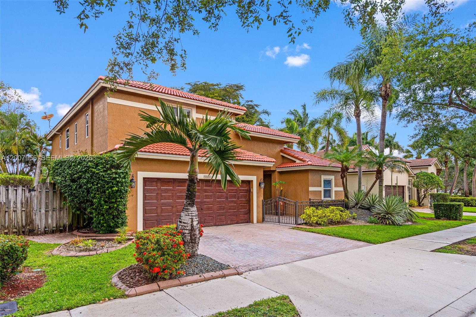 A two-story stucco house with a tile roof, a two-car garage, and palm trees — 16403 Diamond Head Dr, Weston FL 33331, WESTON, FL