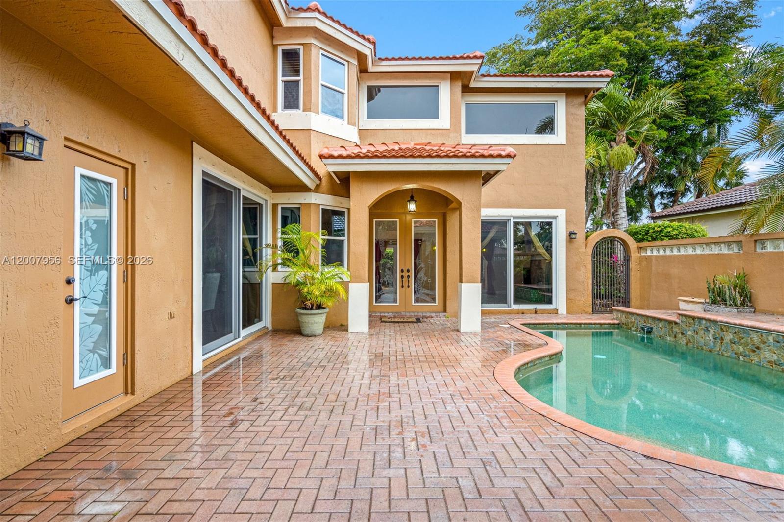 A two-story house exterior features a brick patio, a swimming pool, and arched doorways — 16403 Diamond Head Dr, Weston FL 33331, WESTON, FL