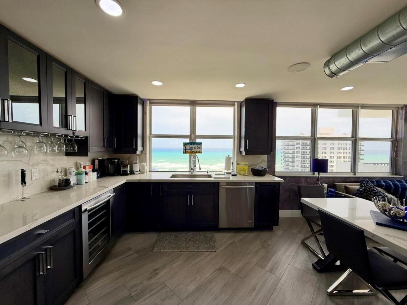 A modern kitchen features dark cabinetry, white countertops, stainless steel appliances, and a scenic ocean view — 2121 N Ocean Boulevard # 1409e, Boca Raton FL 33431, BOCA RATON, FL