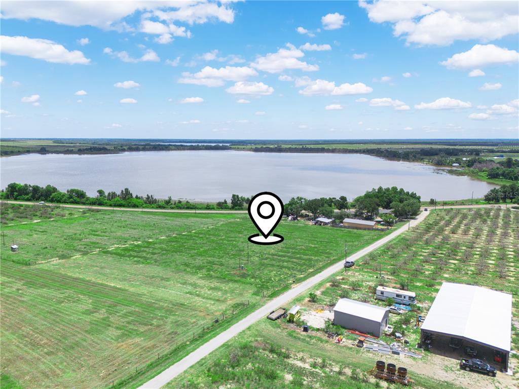 An aerial view shows a large, grassy field with a location pin near a lake — 0 FLOOD ROAD, FROSTPROOF, FL