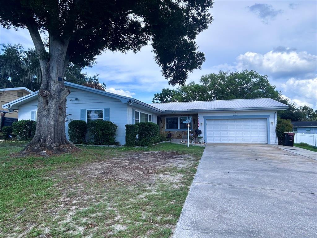A single-story house with a light blue exterior, a metal roof, and a concrete driveway — 1826 6TH STREET SE, WINTER HAVEN, FL