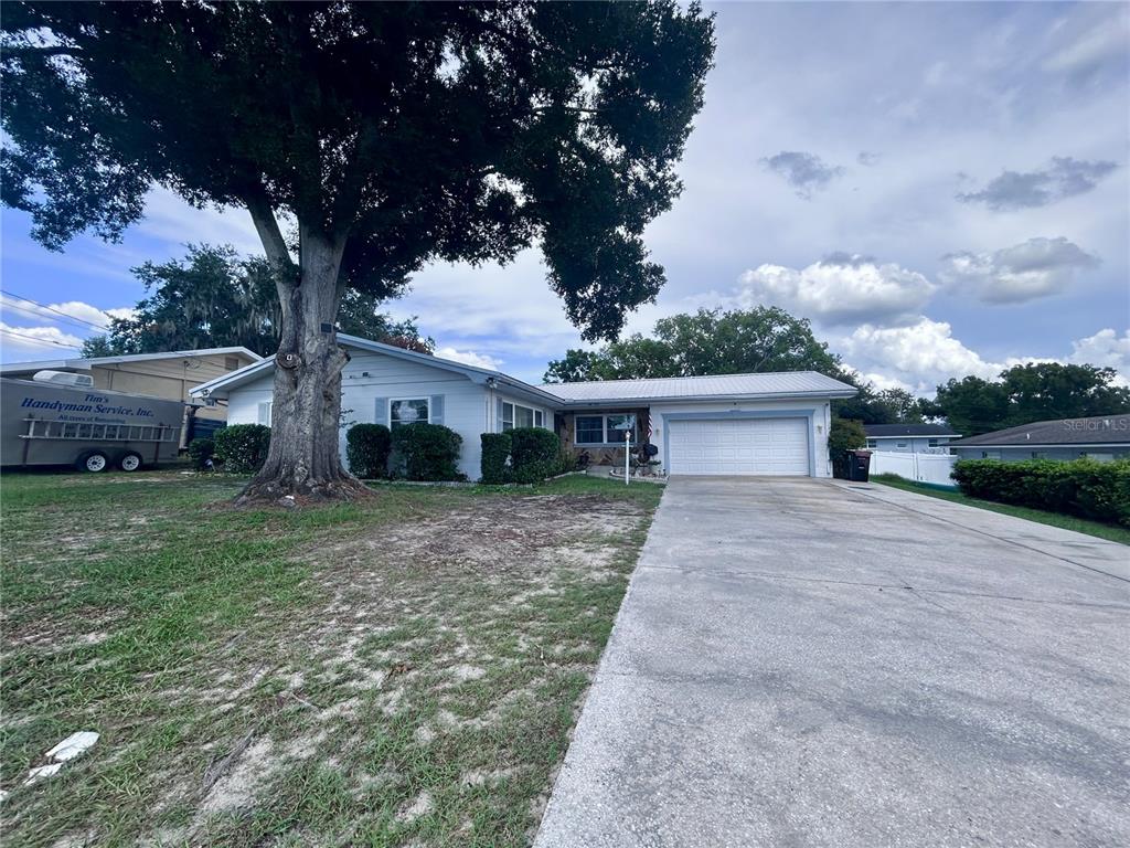 A single-story house with a white exterior, a two-car garage, and a large tree — 1826 6TH STREET SE, WINTER HAVEN, FL