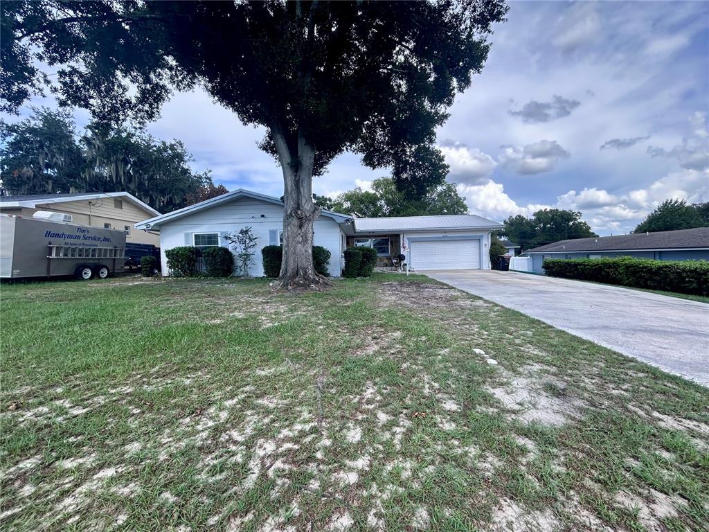 A single-story house with a white exterior, a large tree, and a concrete driveway — 1826 6TH STREET SE, WINTER HAVEN, FL