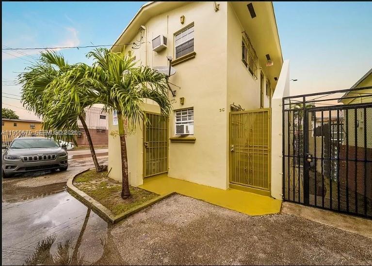 The exterior of a two-story yellow building features a palm tree and metal security gates — 1500 NW 69th Ter, Miami FL 33147, MIAMI, FL