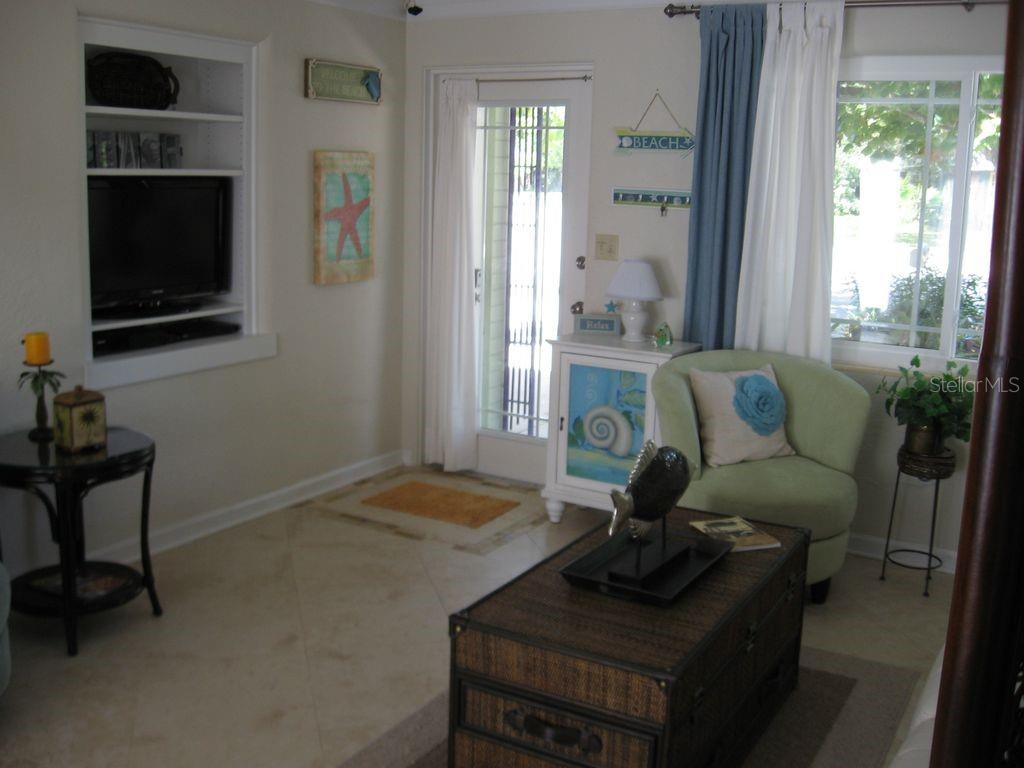 A living room features a built-in television niche, a glass door, and a light green chair — 411 S Pine STREET, NEW SMYRNA BEACH, FL