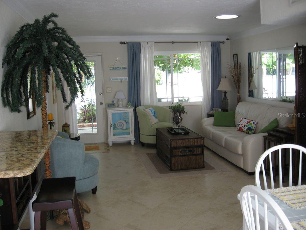 A living room features a white sofa, a trunk coffee table, and a palm tree decoration — 411 S Pine STREET, NEW SMYRNA BEACH, FL