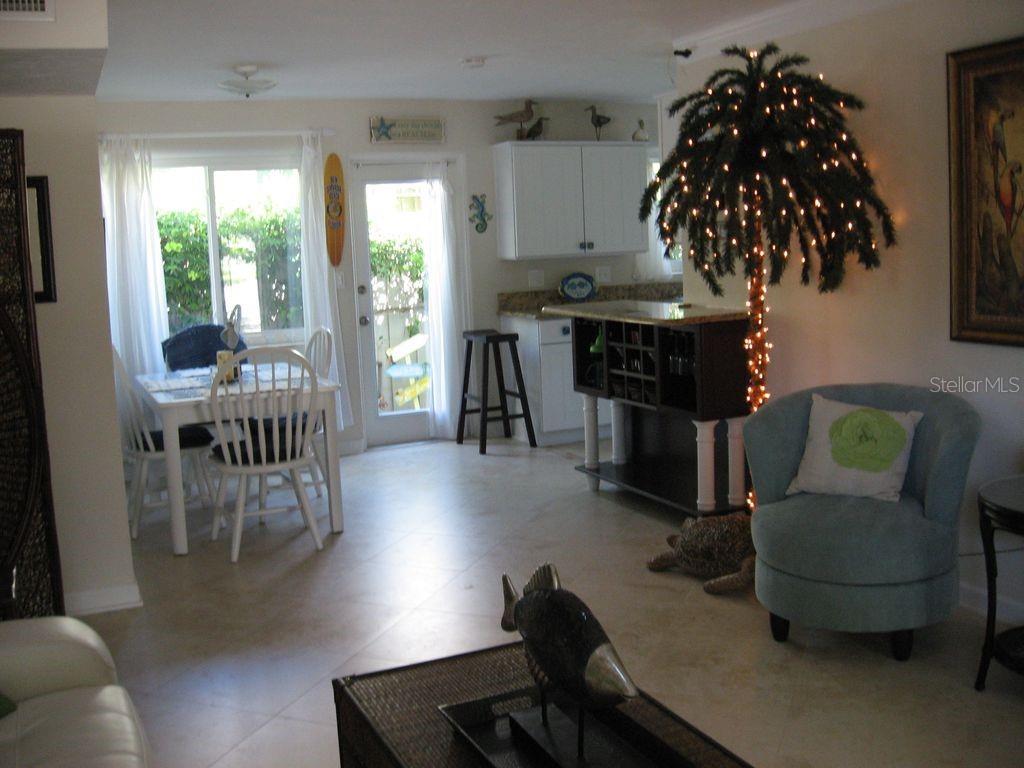 A dining area and living space feature tile floors, a lighted palm tree, and furniture — 411 S Pine STREET, NEW SMYRNA BEACH, FL