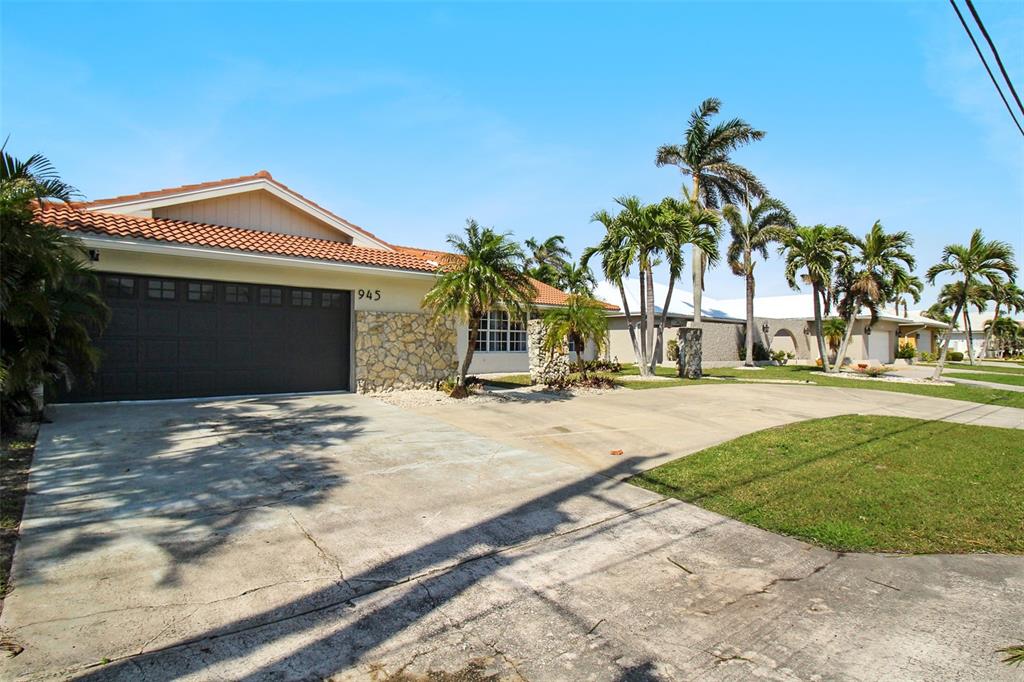 A single-story house with a tile roof, stone facade, and a concrete driveway with palms — 945 BAL HARBOR BOULEVARD, PUNTA GORDA, FL
