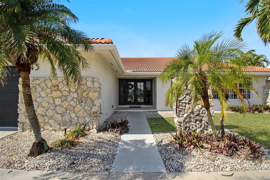 The exterior of a single-story house features a stone facade, a tiled roof, and palm trees — 945 BAL HARBOR BOULEVARD, PUNTA GORDA, FL
