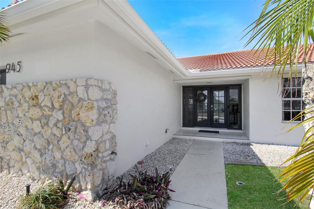 The exterior of a white house features a stone accent wall and a double front door — 945 BAL HARBOR BOULEVARD, PUNTA GORDA, FL