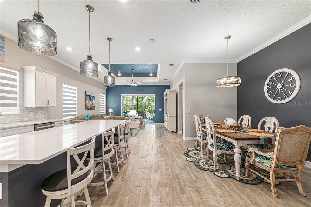 An open-concept kitchen and dining area features a large island, pendant lighting, and wood-look flooring — 8876 SW 59TH LANE ROAD, OCALA, FL