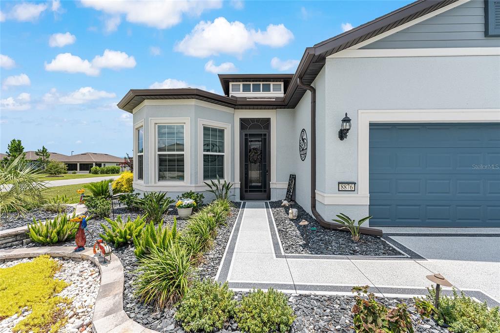 The exterior of a house features a paved walkway leading to a dark-framed front door — 8876 SW 59TH LANE ROAD, OCALA, FL