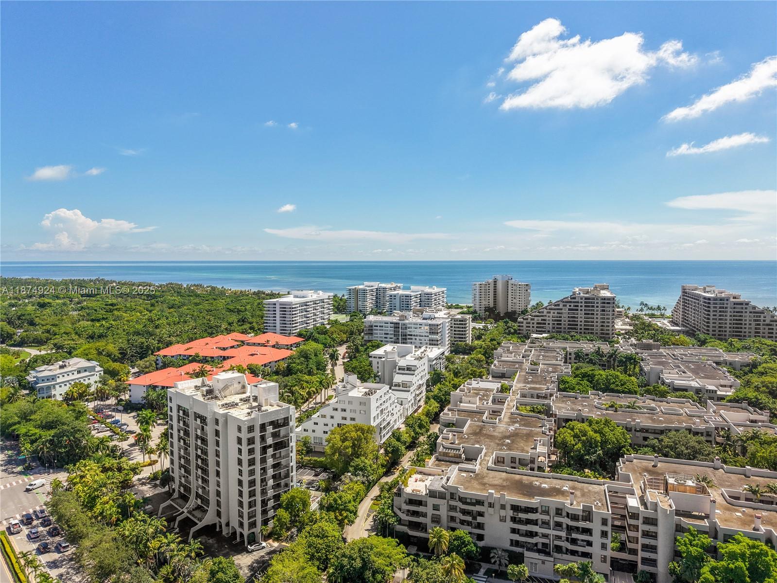 An aerial view shows multiple apartment buildings surrounded by lush trees near the ocean — 101 Crandon Blvd # 381, Key Biscayne FL 33149, KEY BISCAYNE, FL