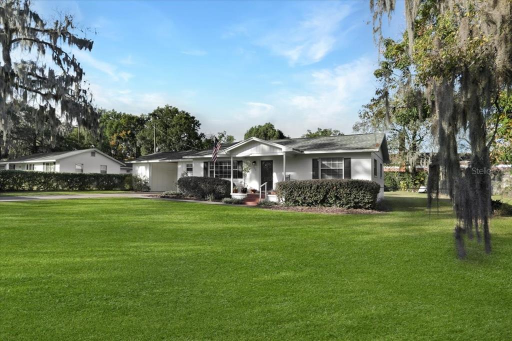 A white single-story house with a carport and a large front lawn — 220 SE 28TH AVENUE, OCALA, FL