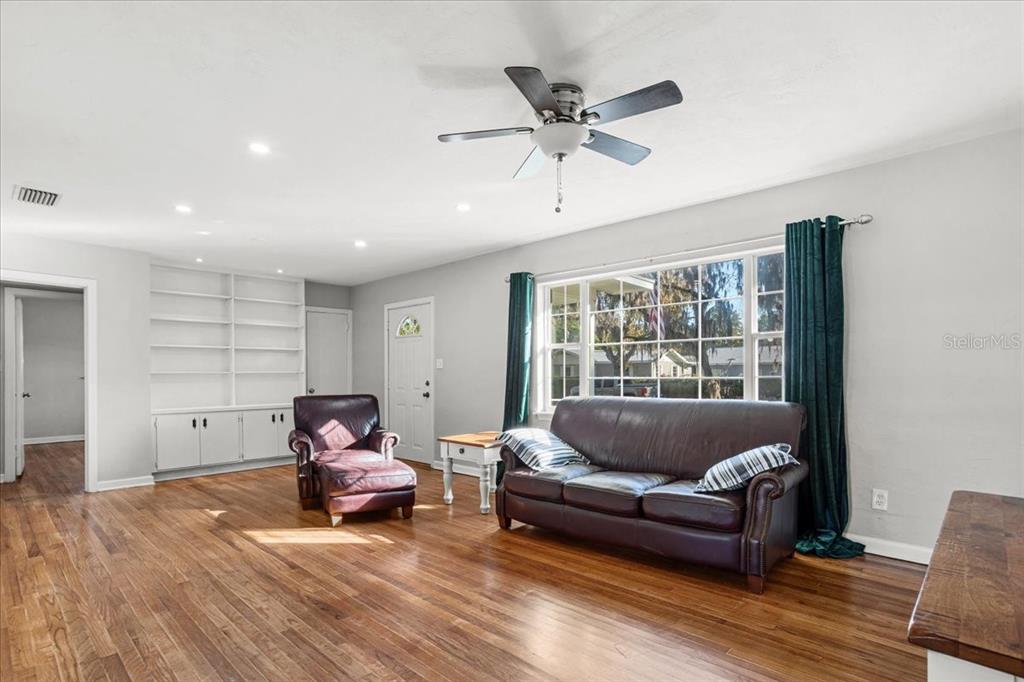 A living room features hardwood floors, a leather sofa, a matching armchair, and built-in shelving — 220 SE 28TH AVENUE, OCALA, FL