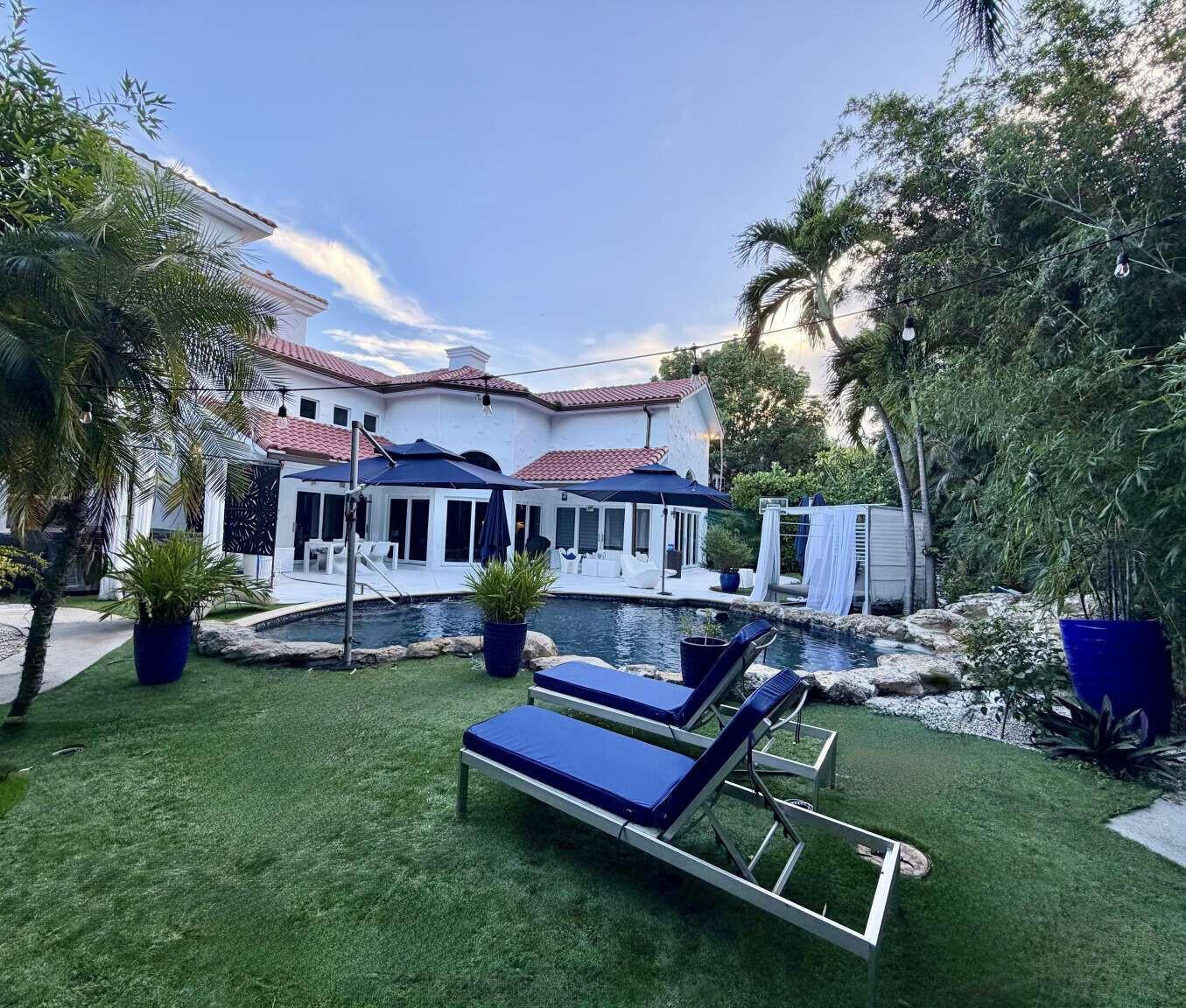 A backyard features a swimming pool, two blue lounge chairs, and a white house — 233 Pershing Way, West Palm Beach FL 33401, WEST PALM BEACH, FL