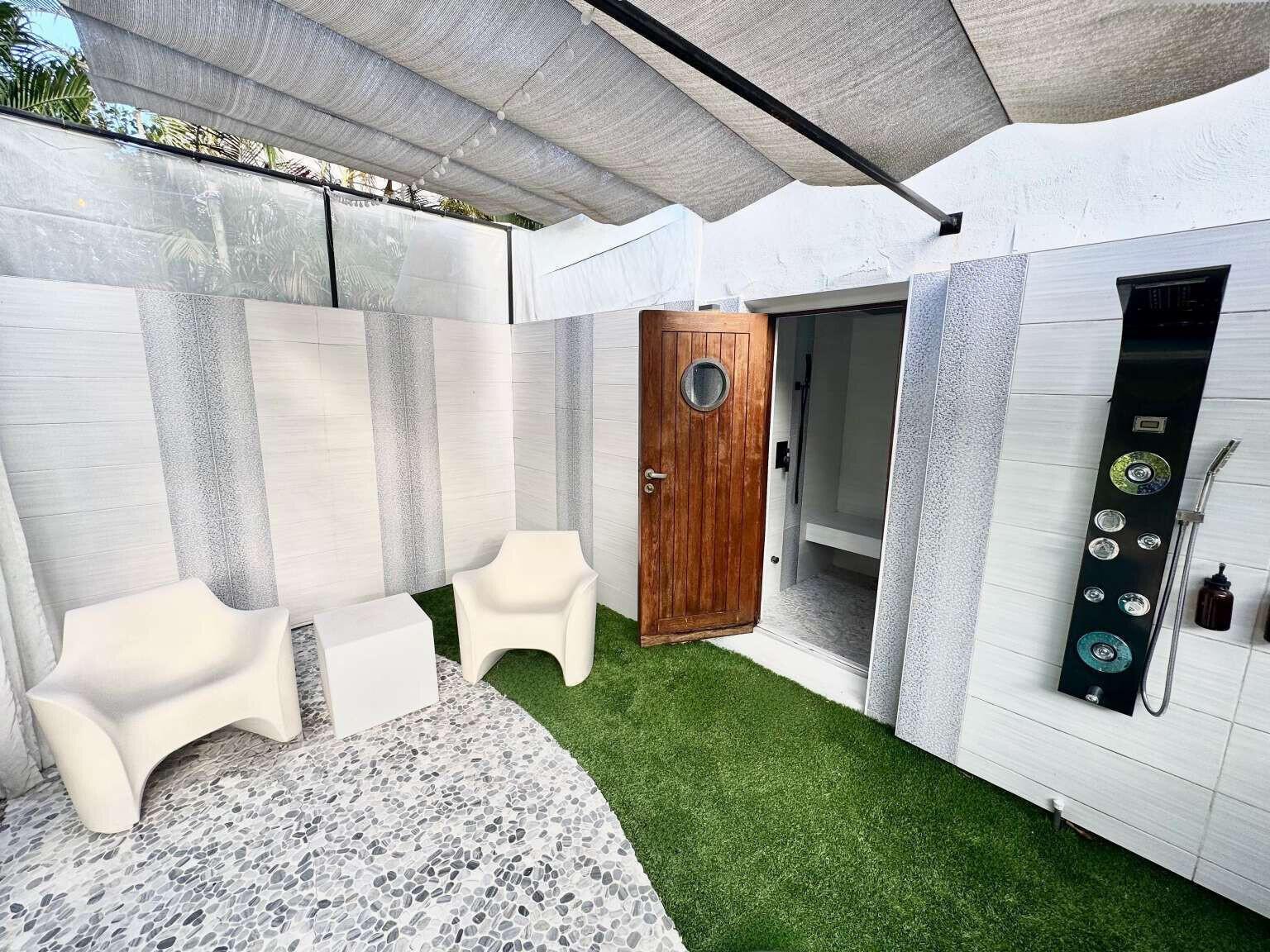 A backyard swimming pool features a rock waterfall, blue umbrella, and white lounge chair — 233 Pershing Way, West Palm Beach FL 33401, WEST PALM BEACH, FL