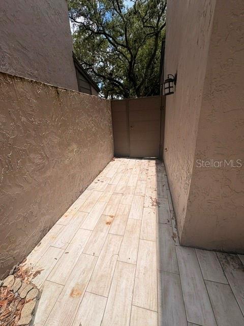 A narrow outdoor walkway features light-colored tile flooring and a wooden gate at the end — 459 MEADOWOOD BOULEVARD, FERN PARK, FL