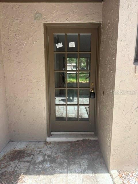 A brown glass-paneled door is set into a beige stucco exterior wall — 459 MEADOWOOD BOULEVARD, FERN PARK, FL