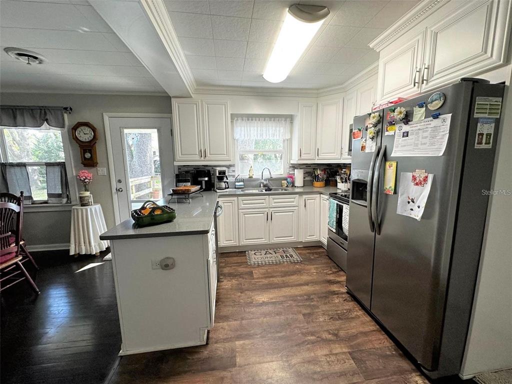 A kitchen features white cabinets, gray countertops, stainless steel appliances, and wood-look flooring — 1774 NE 12TH STREET, OCALA, FL