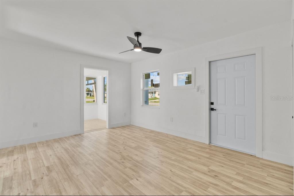 A bright room with light wood-look flooring, a ceiling fan, and a white entry door — 2352 EDNOR STREET, PORT CHARLOTTE, FL