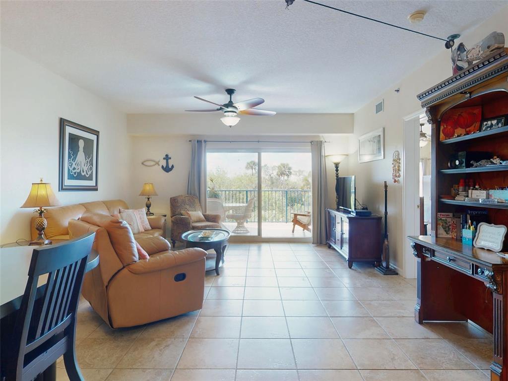 A living room with tile floors, a ceiling fan, and sliding glass doors to a balcony — 5300 S ATLANTIC AVENUE UNIT 6-206, NEW SMYRNA BEACH, FL