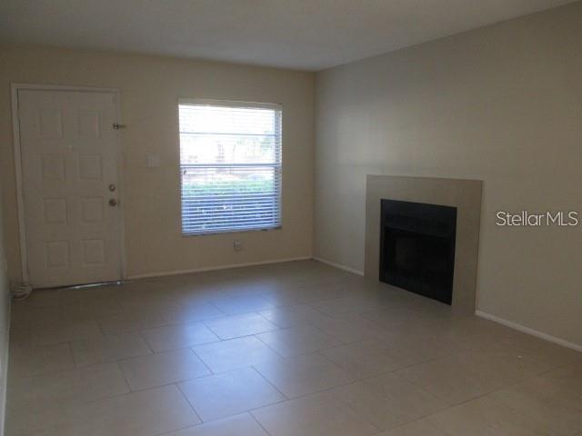 A living room features light-colored tile flooring, a fireplace, and a white entry door — 14227 SHADOW MOSS LANE UNIT 102, TAMPA, FL